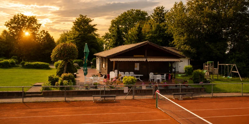 Tennis clubhouse and courts during golden hour with warm lighting