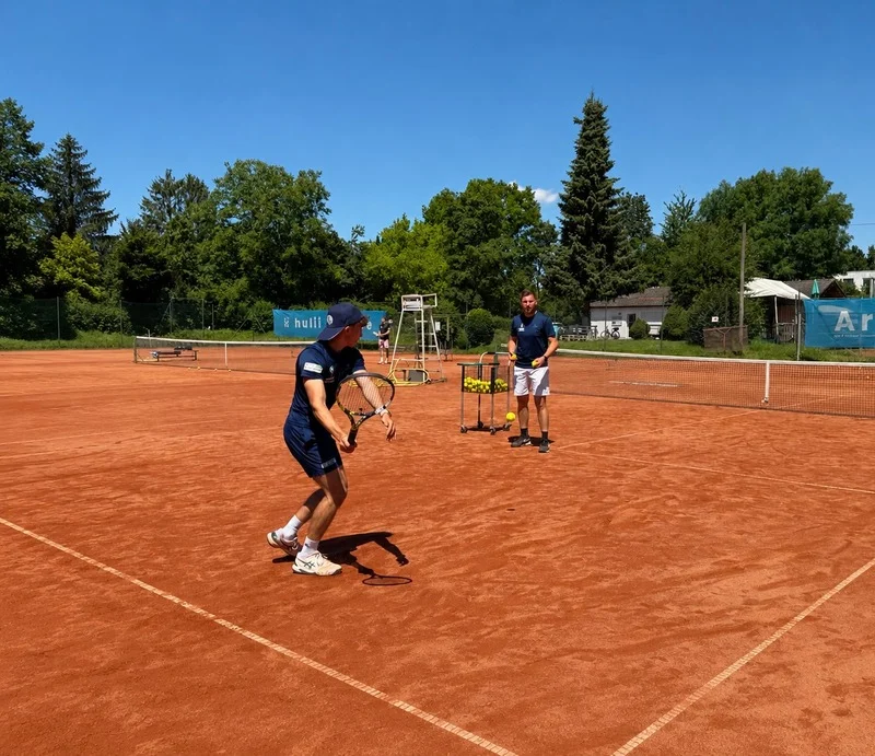 Einzeltraining auf dem roten Sandplatz mit Trainer und Spieler